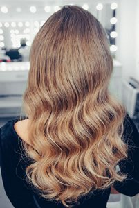 Woman with dark blonde hair styled in Hollywood waves